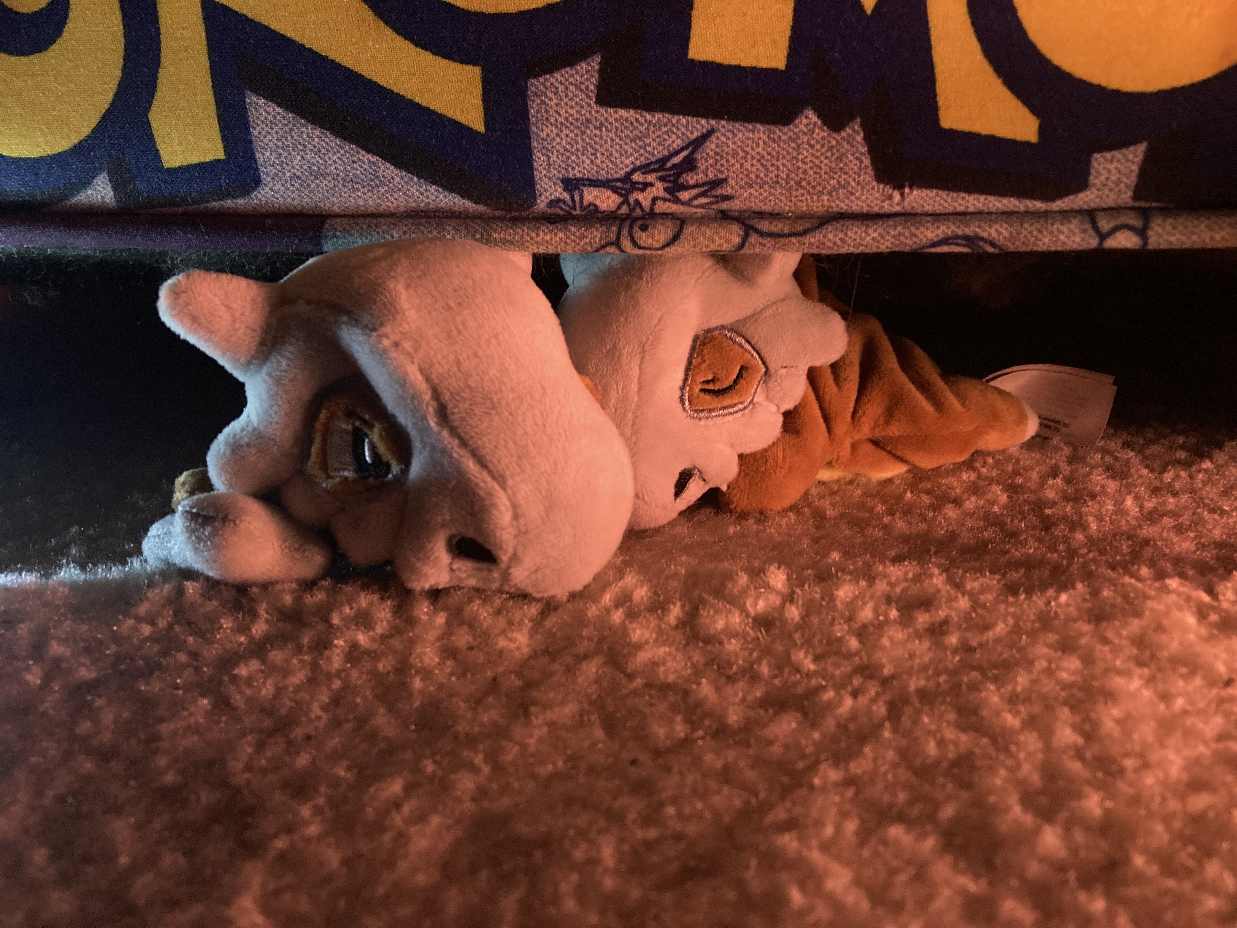 Two Cubone blushies hiding under a Pokemon chair.